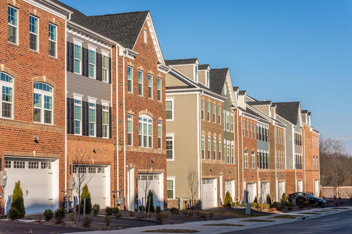 A row of brick townhomes each have a garage on the ground floor.
