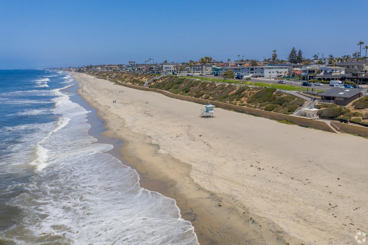 An aerial view of Carlsbad State Beach shows the waves crashing onto the shore.