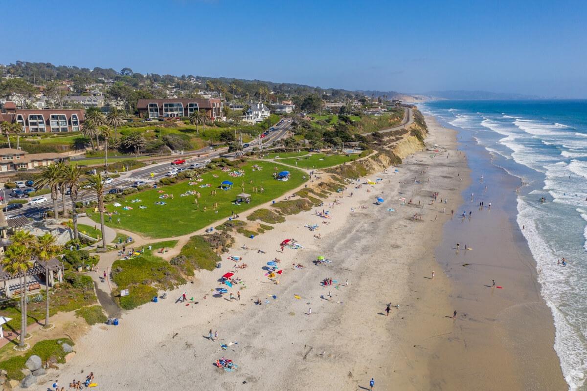An aerial view of Del Mar shows beachgoers lounging on the sand.