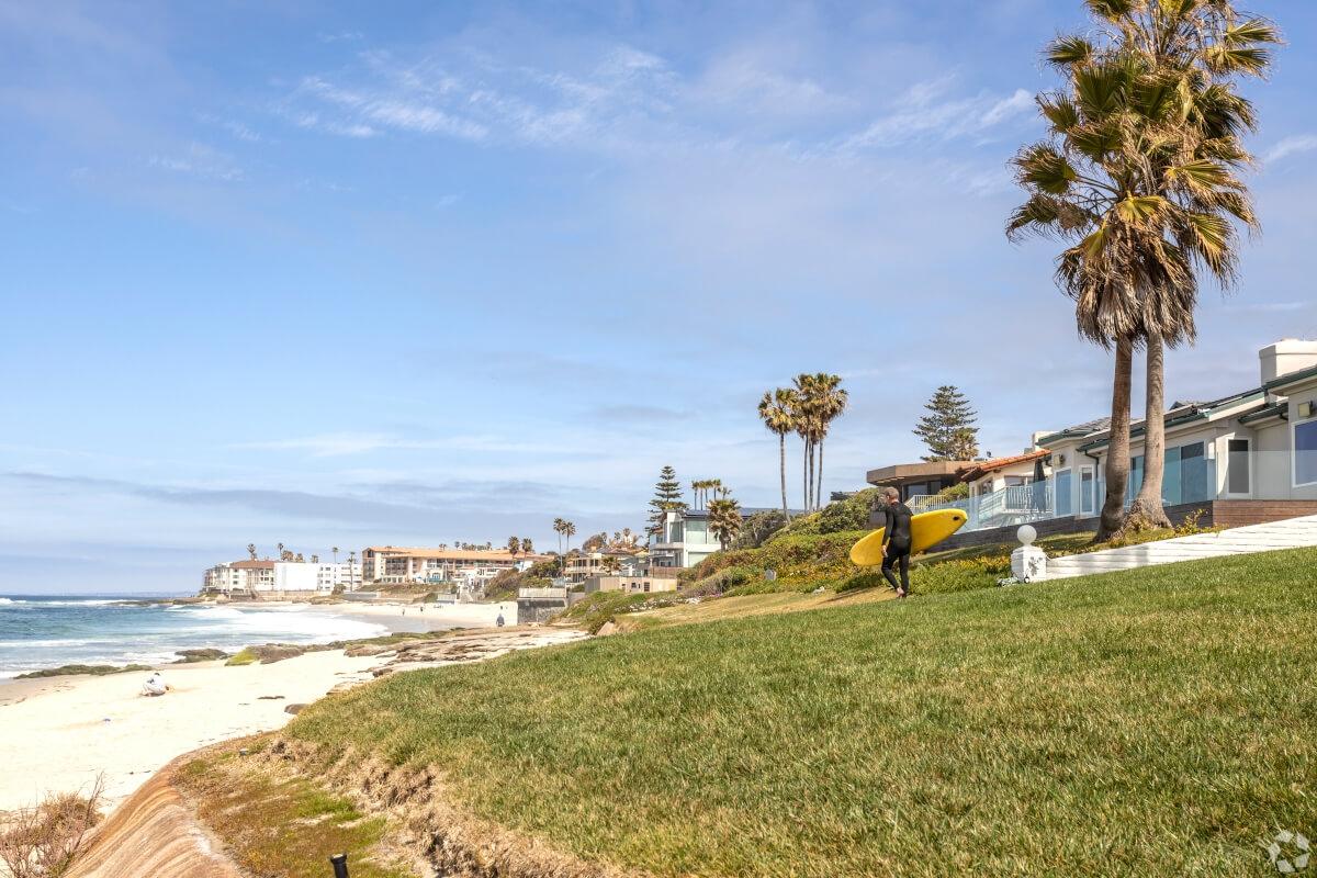 A man carries a yellow surfboard to Windansea Beach.