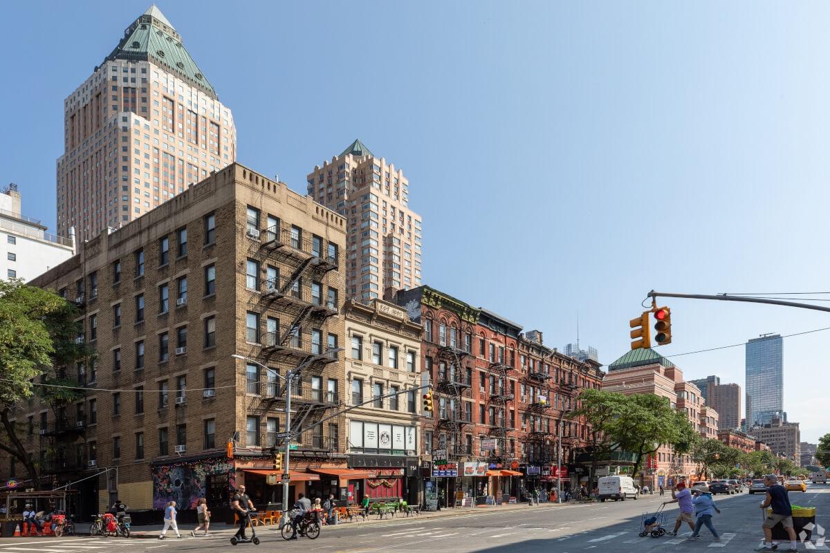 Angled shot of walk-up apartments with a large building in the background.