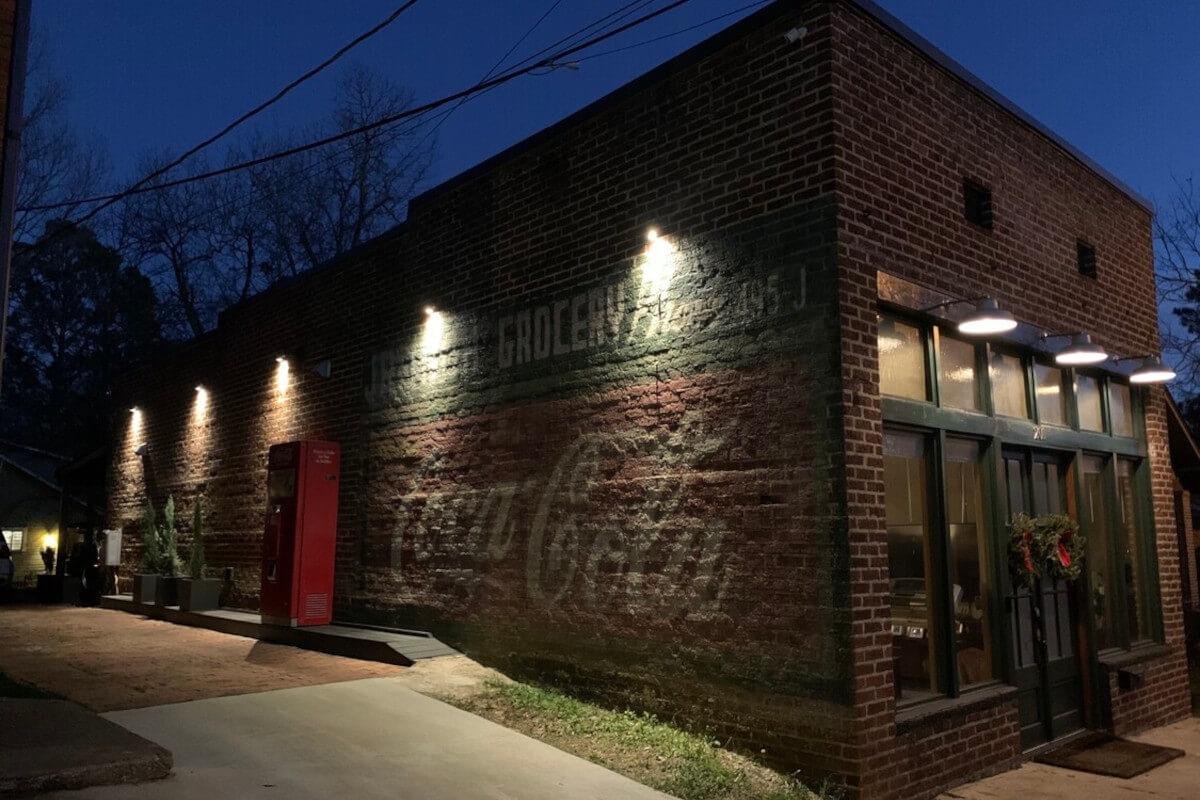 Floodlights illuminate the Jr. High Grocery sign painted on the brick exterior at 201 Louisville Street in Starkville, MS.