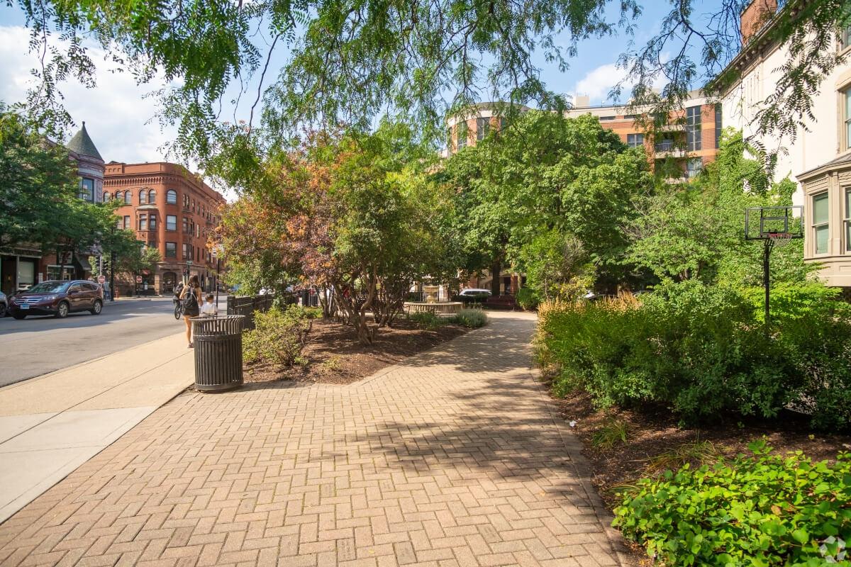 A view of brick sidewalks, lush greenery, and Victorian buildings in Lincoln Park.