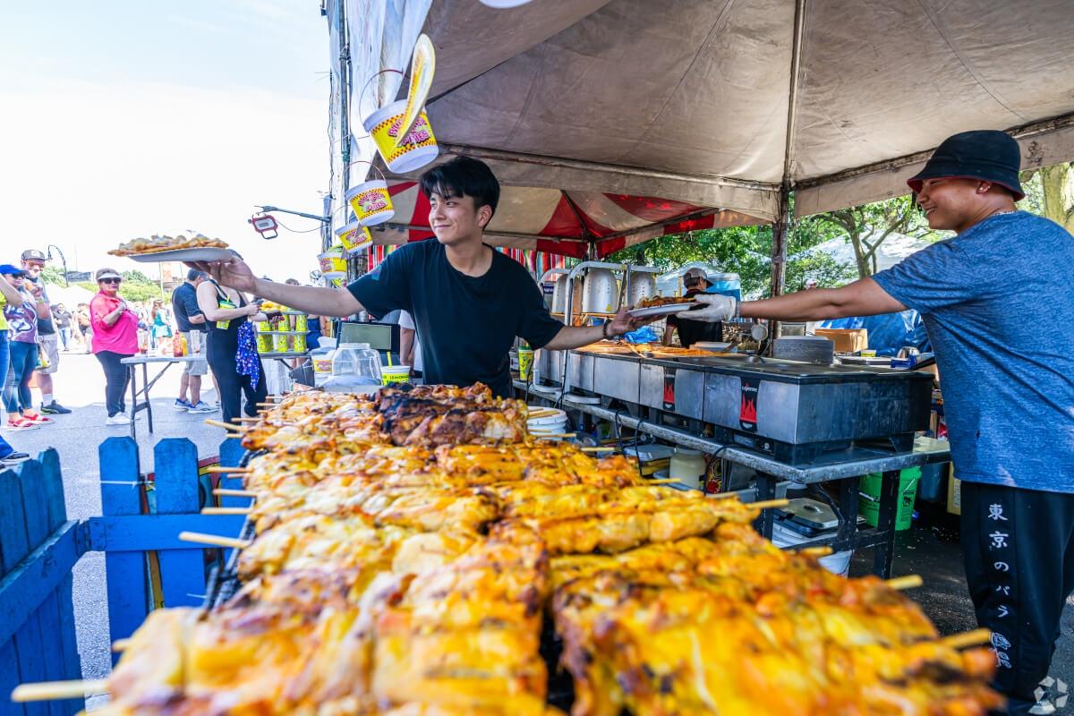 A food vendor at Logan Square Arts Festival serves chicken skewers.