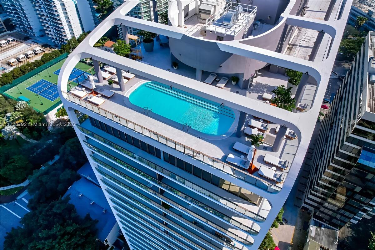 A rooftop pool lies under a curving roof adornment.
