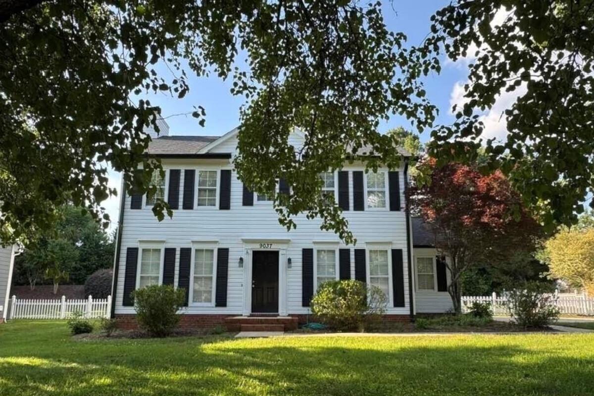 9037 Castlebay Drive is a white Colonial-style home with a white picket fence.