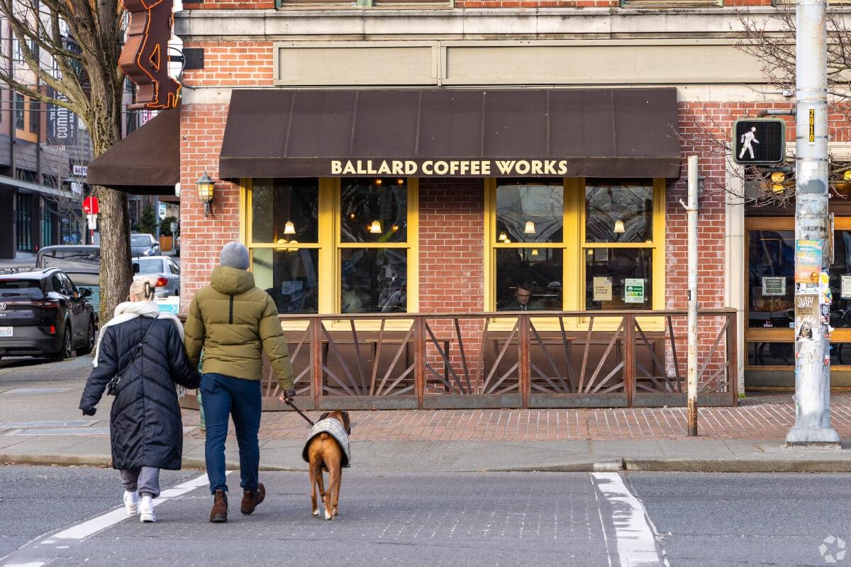 A couple walks their dog toward Ballard Coffee Works in the Ballard neighborhood.