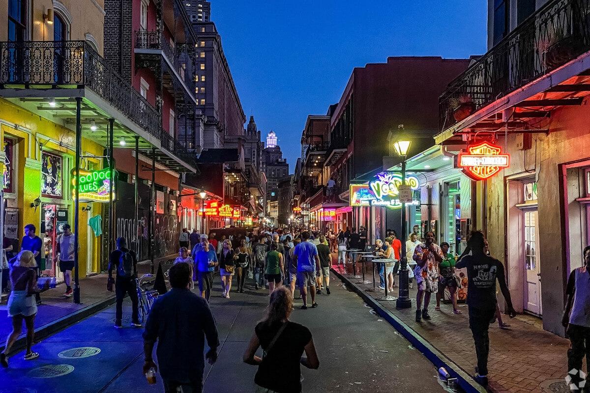 Hundreds of people walk down Bourbon Street in the French Quarter at night.
