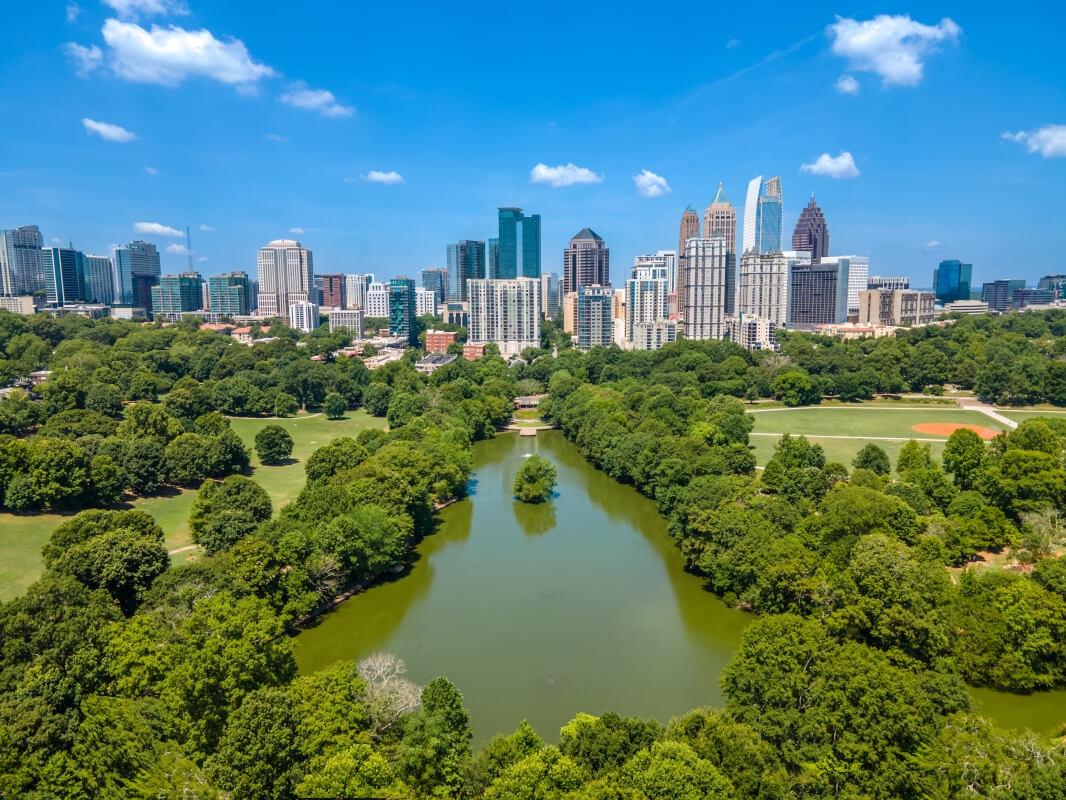 An aerial view of sunny Piedmont Park with the Atlanta skyline in the background