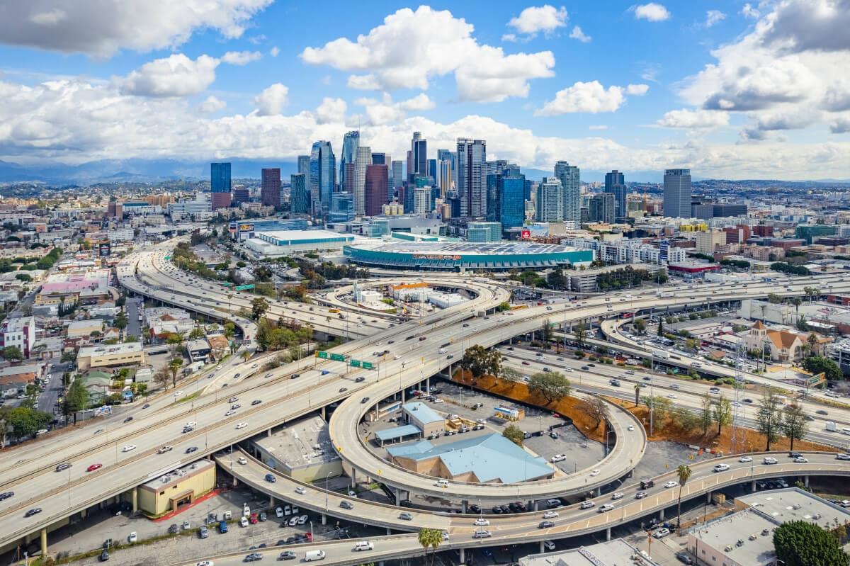 Los Angeles skyline rises behind the network of highways.