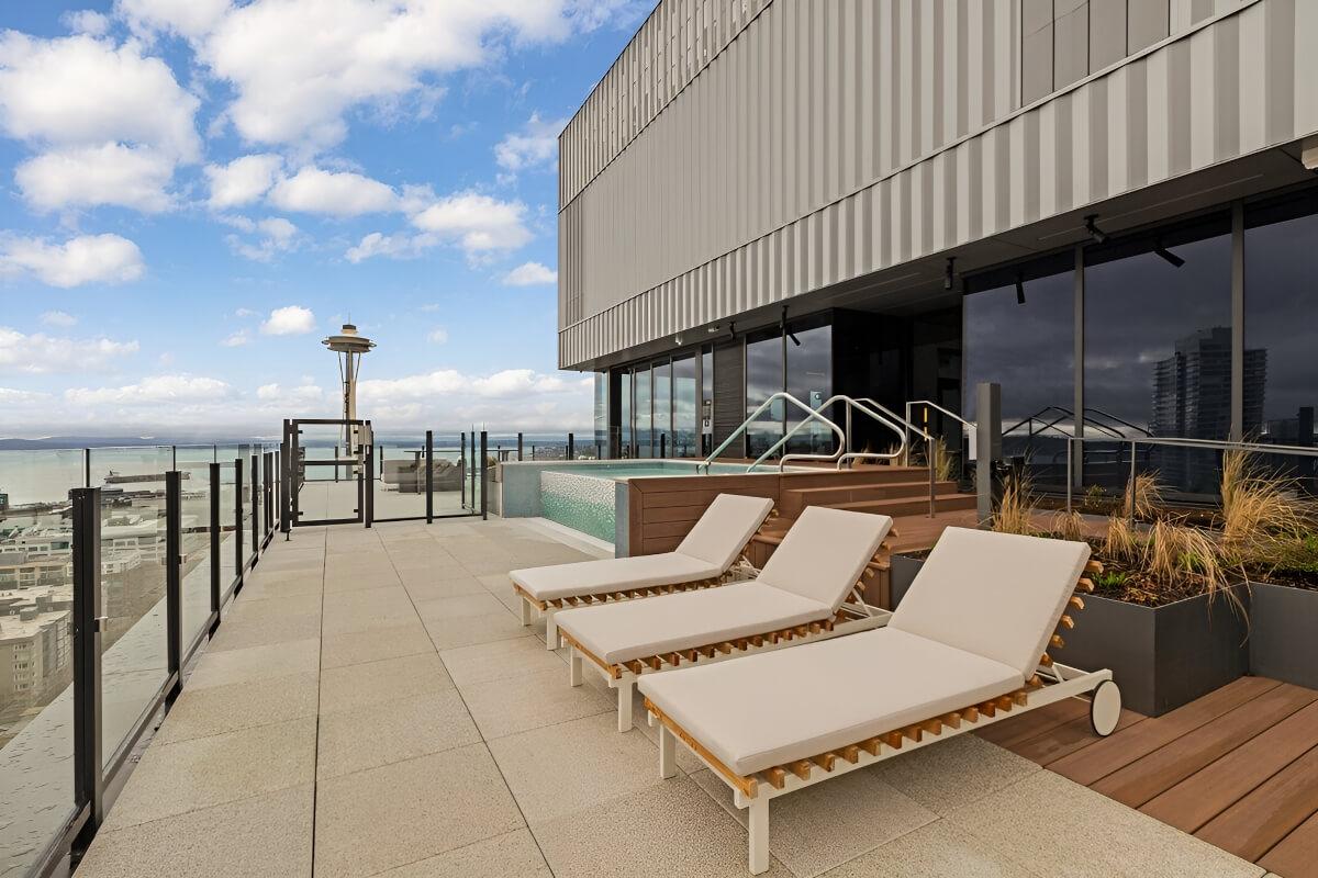 Lounge chairs sit next to a rooftop pool.