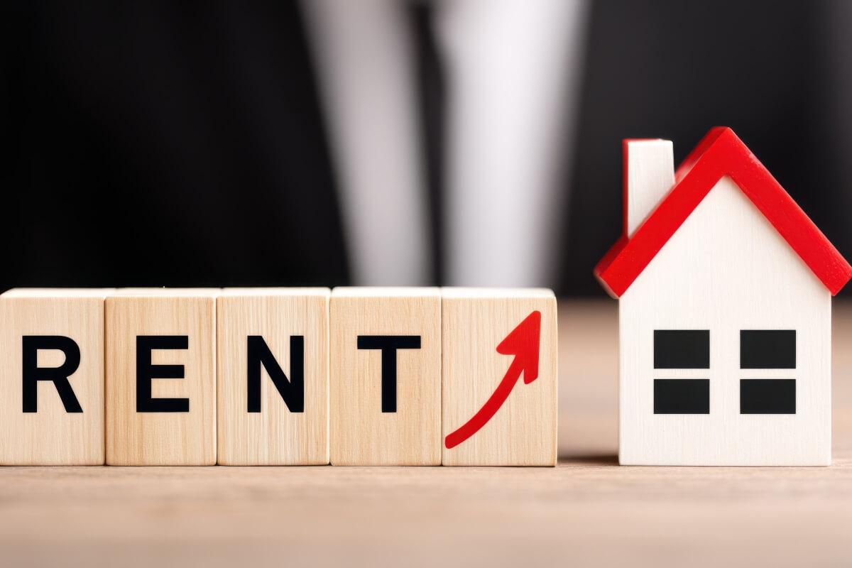 Blocks that spell out rent with an arrow going up at the end next to a house.
