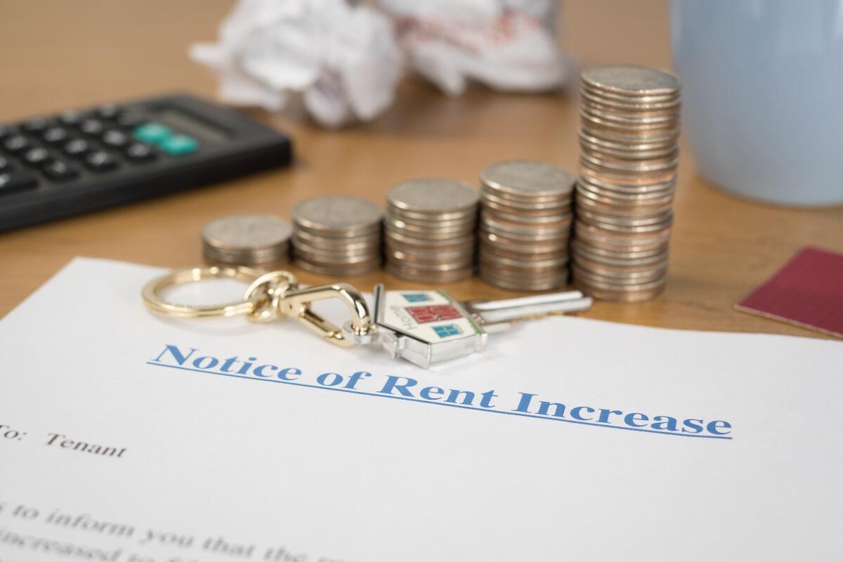 Stack of coins getting bigger and bigger on top of notice to rent increase.