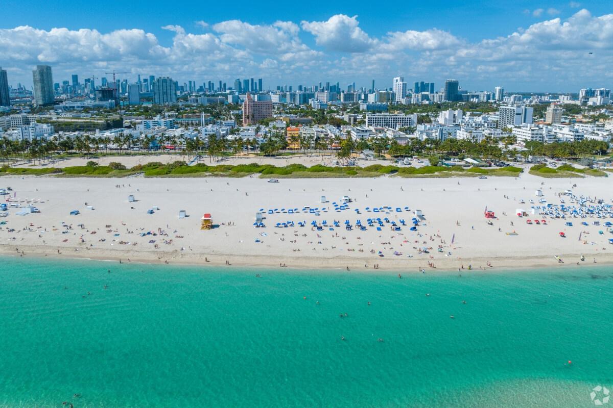 An aerial view of the sandy beach at Lummus Park in Miami with the Downtown Miami skyline in the background.