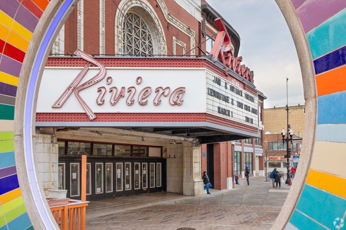 The historic Riviera Theatre marquee framed through a colorful circular structure, with pedestrians nearby.