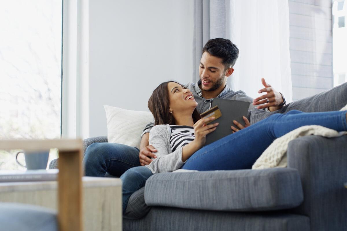 Man and woman laying on couch looking at tablet.