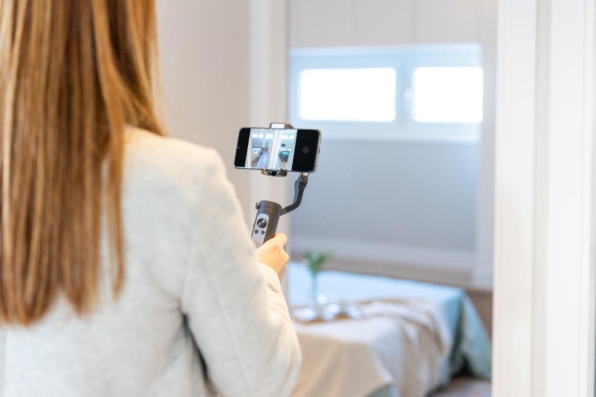 Woman filming home on her phone.