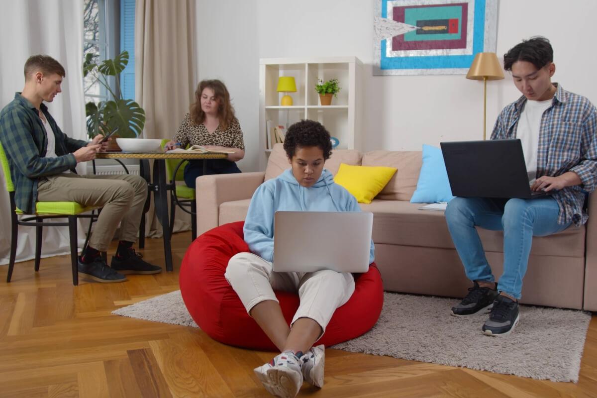 A group of students on electronic devices in their apartment.