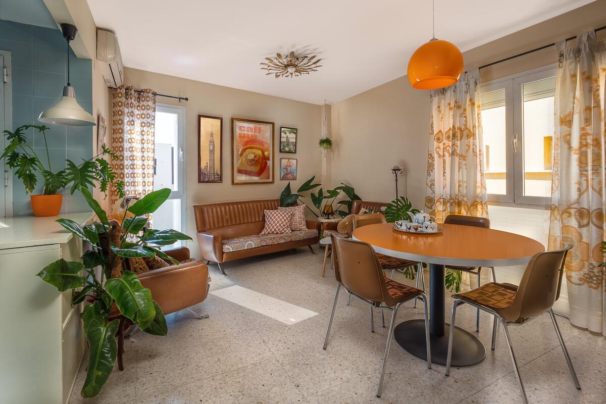 A small living area has 70s-style seating, mod lighting, and quirky curtains.