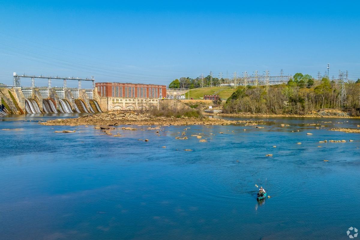 Wide view of the Chattahoochee River and dam in Columbus GA with kayakers — highlighting riverfront apartment living and outdoor recreation.
