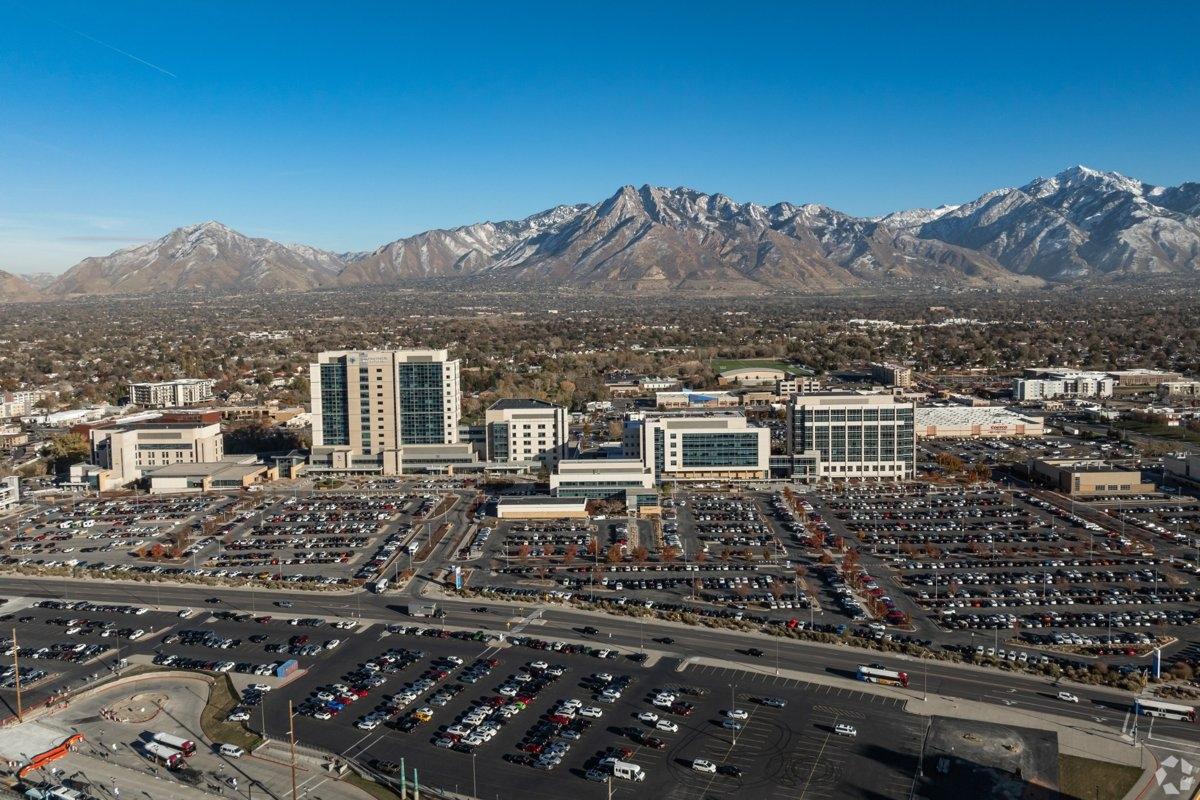 Aerial view of Murray City Center with office buildings and Wasatch Mountains in the background, highlighting city accessibility and nearby apartment complexes.