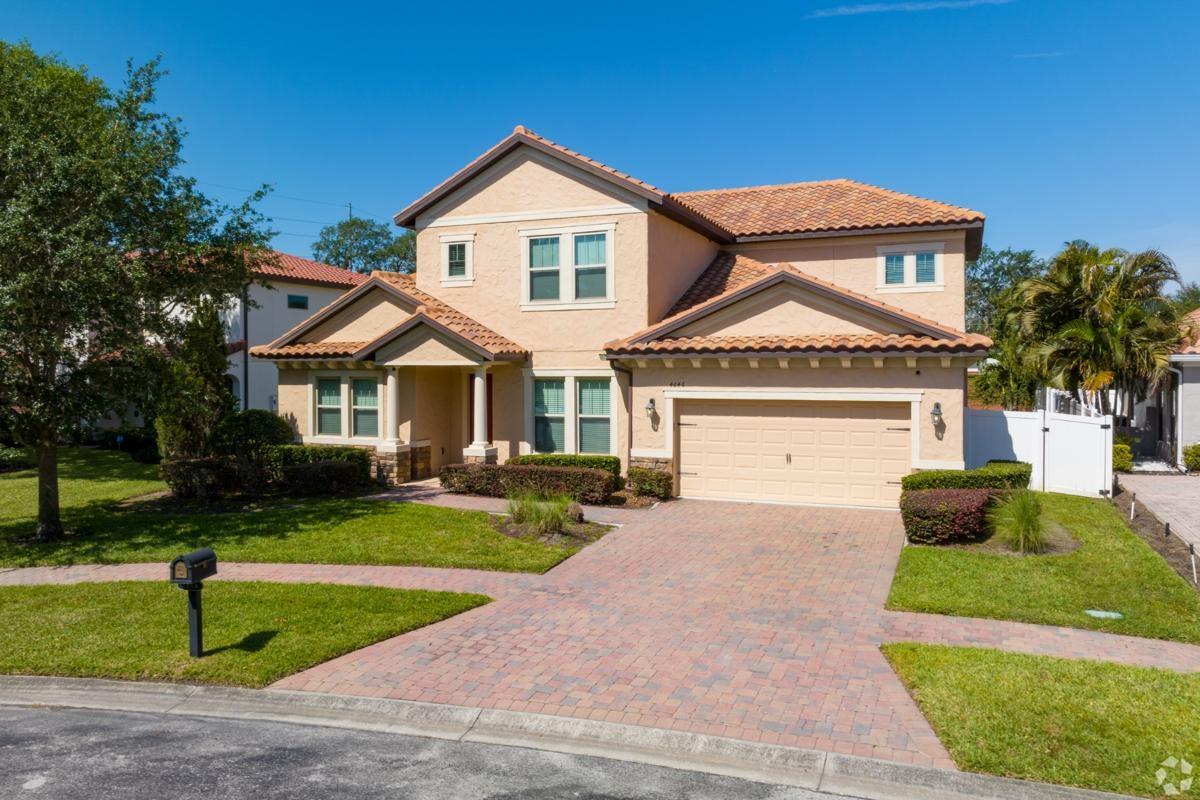 Front view of a suburban stucco house with terracotta roof and brick driveway in Winter Park, ideal for families seeking homes near Orlando apartment communities.