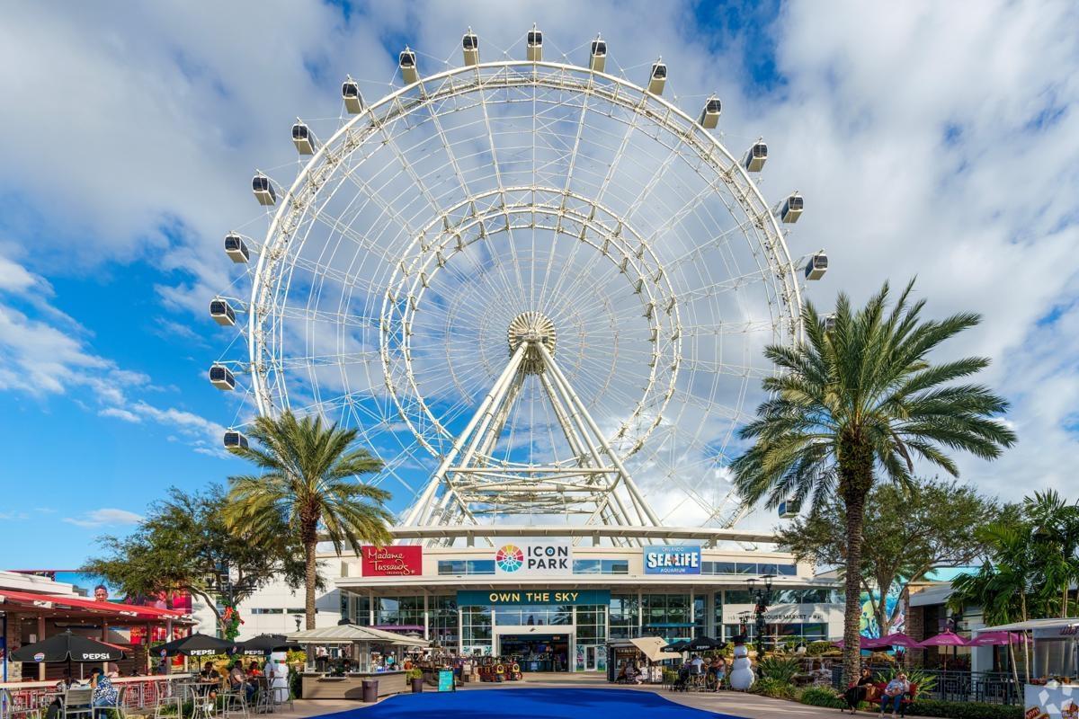 Iconic Ferris wheel at ICON Park in Orlando with palm trees and visitors below, an entertainment hub popular with apartment residents in the area.