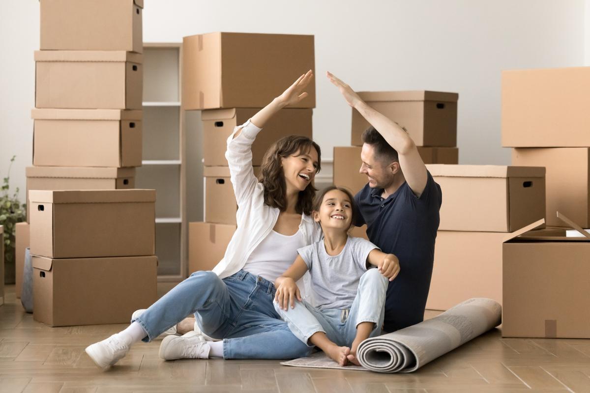 Happy family sitting among moving boxes in their new apartment, symbolizing the excitement of relocating to a modern rental home.