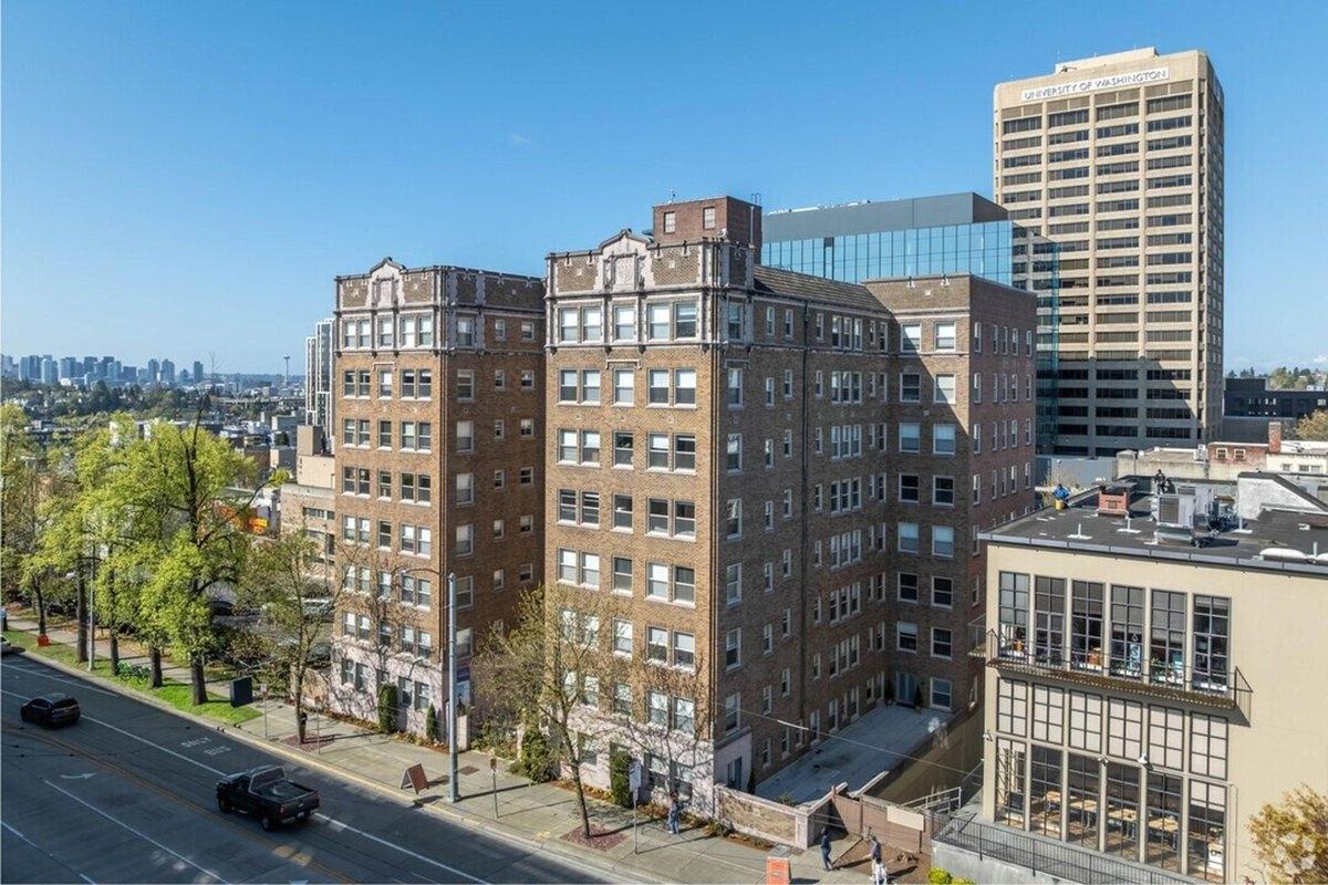 The historic Malloy Apartment Homes in Seattle, WA, with city skyline in the background – ideal for renters seeking classic brick architecture near downtown.