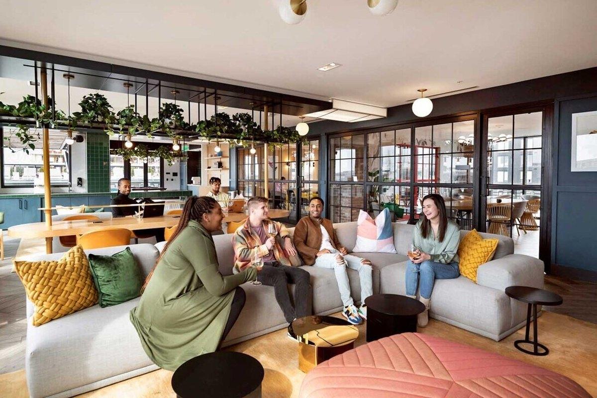 Group of young renters relaxing in a cozy shared living space with large windows and modern furnishings — ideal for apartment co-living settings.