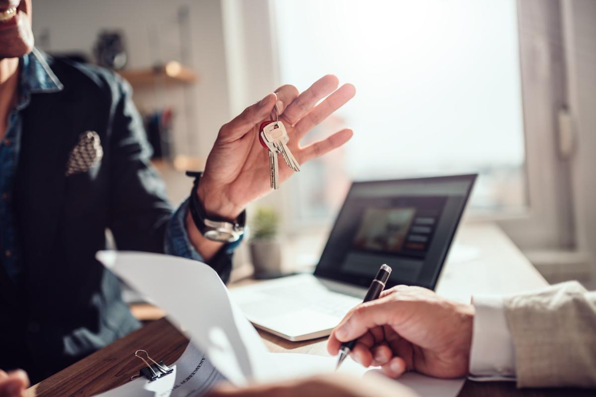 Landlord handing over house keys during lease signing, highlighting when renters insurance is required.