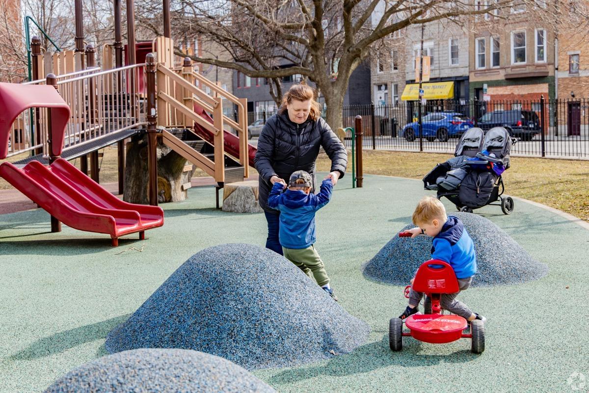 Children playing and families interacting in a neighborhood playground in Wicker Park, ideal for apartment dwellers with kids.