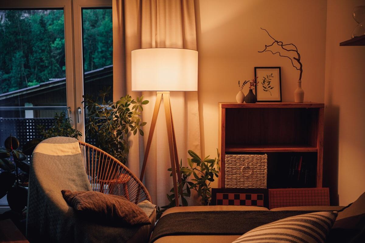 A view of a cozy corner in a living room lit up by a lamp.