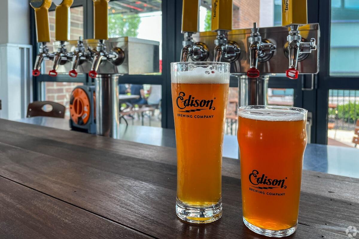 Two glasses of beer on a bar top.