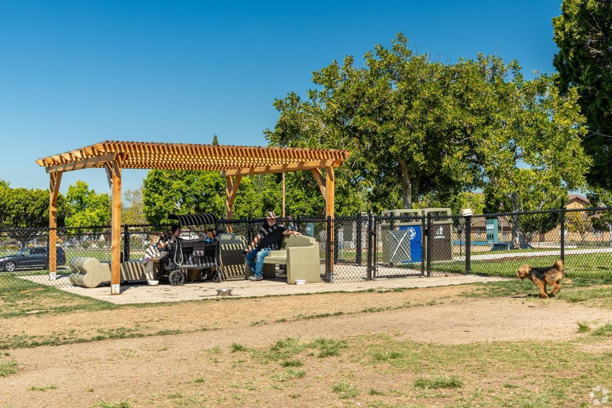 Community dog park in Allied Gardens with covered seating and open grass, offering pet amenities for family-friendly apartments.