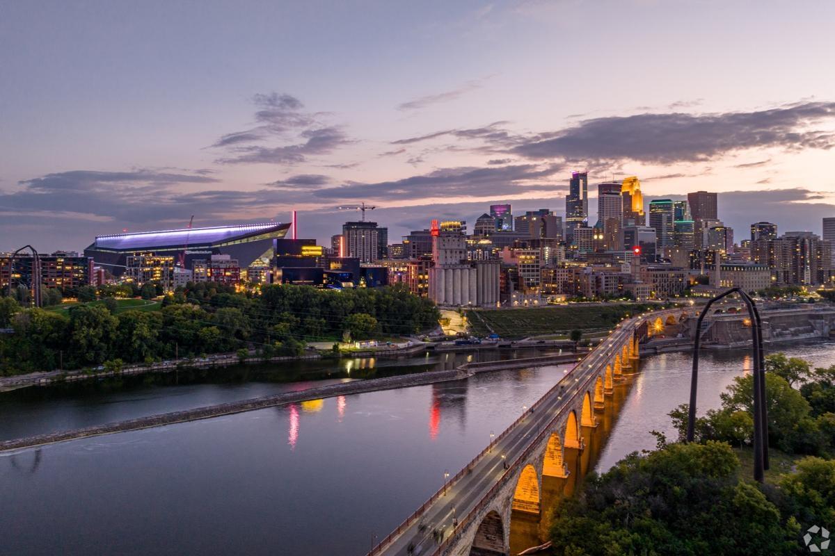 Dusk view of downtown Minneapolis, Minnesota with the Stone Arch Bridge and U.S. Bank Stadium, offering scenic views near the riverfront.