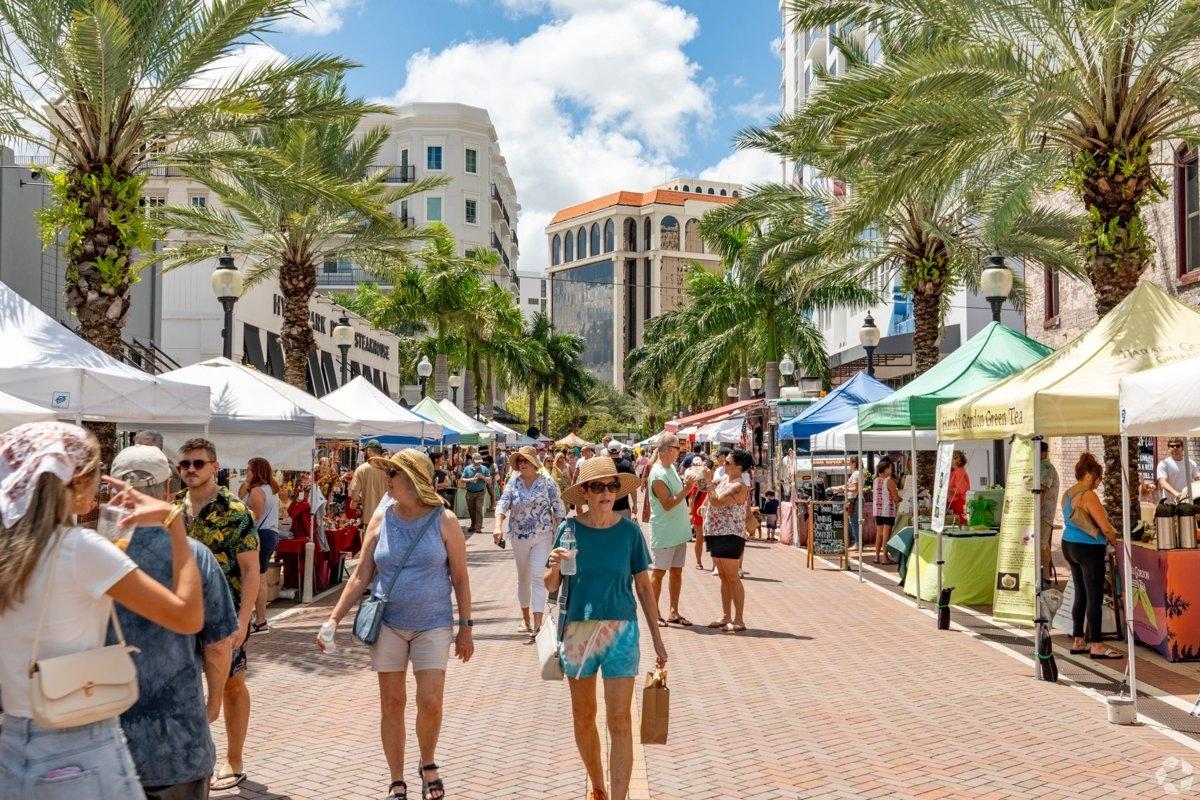 Bustling Sarasota FL farmers market surrounded by palm trees and high-rise apartments — perfect for apartment seekers wanting vibrant coastal living.
