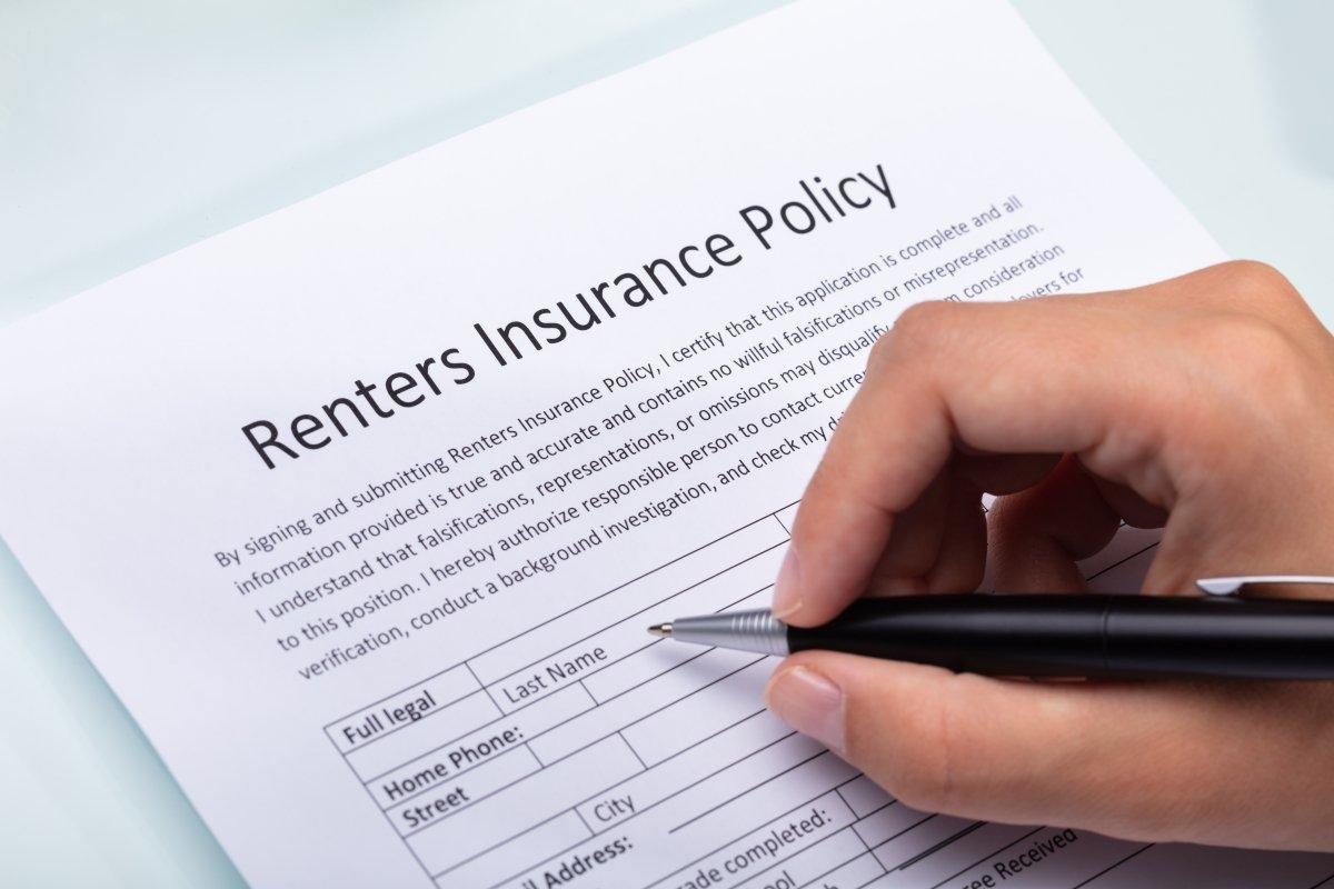 Hand filling out renters insurance policy.