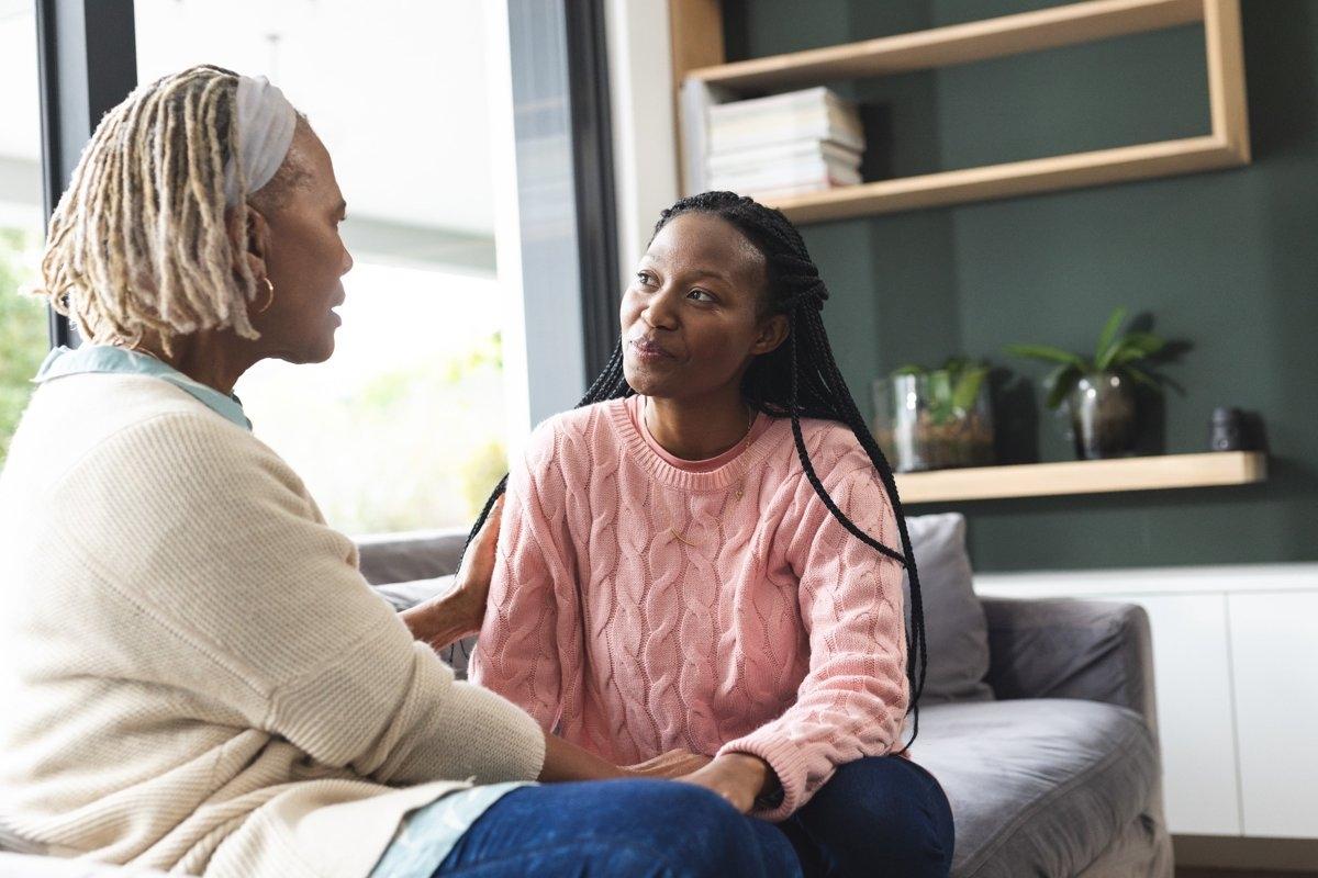 Daughter and mother sitting on couch and talking.