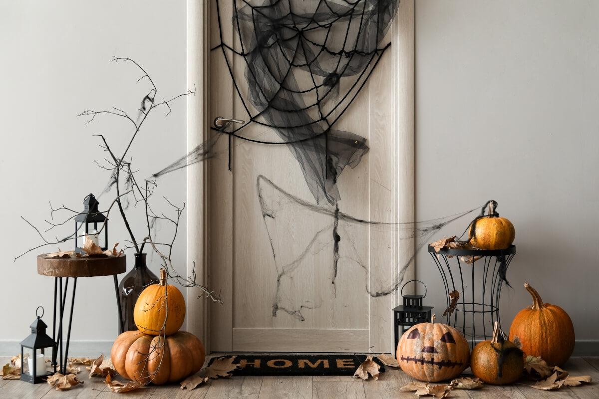 Pumpkins and cobwebs decorate an apartment door.