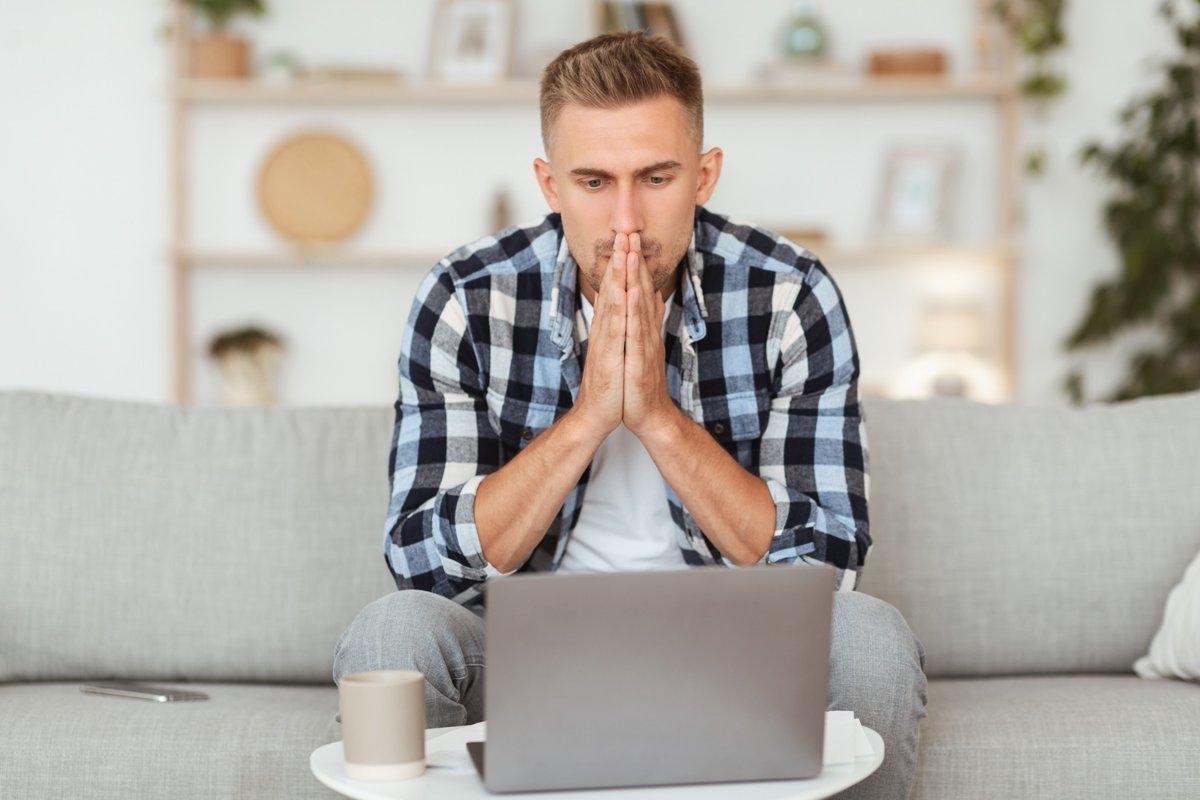 Guy on sofa looking a his computer trying to make a decision
