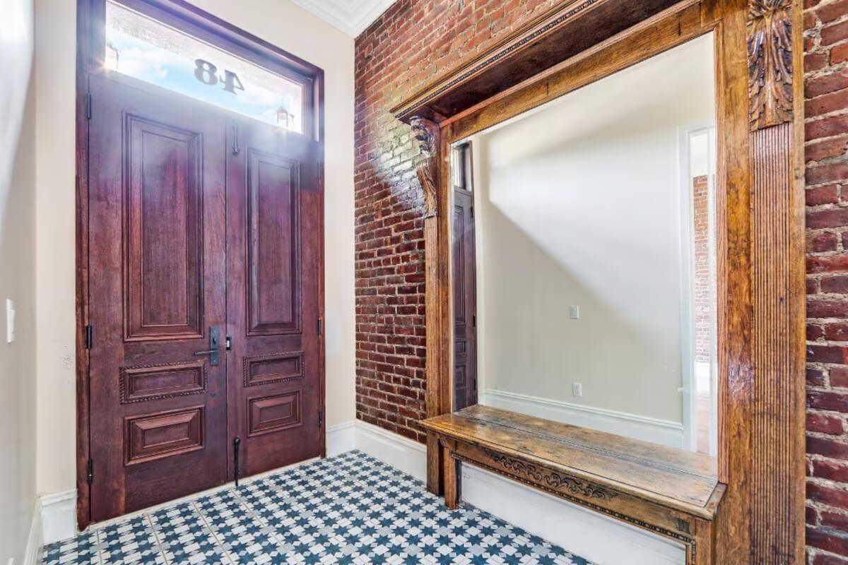 The entryway at 48 West 120th Street in Manhattan has an exposed brick wall and unique tile flooring.