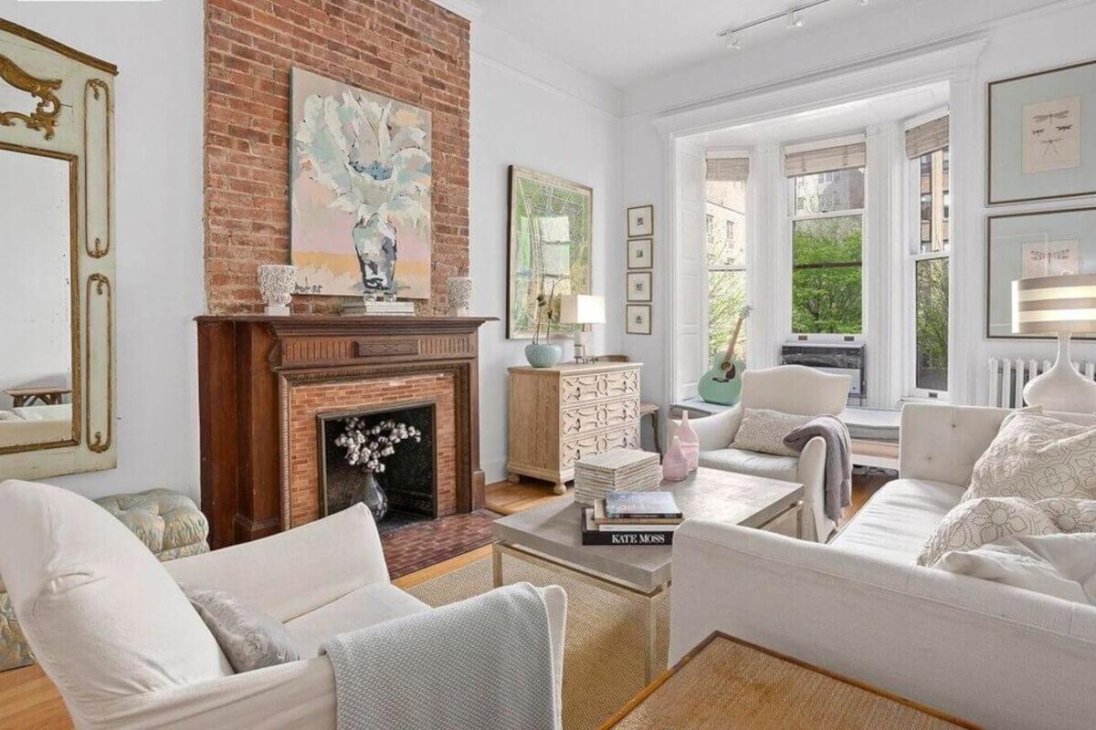 The living room at 54 East 83rd Street has a bay window and a brick fireplace.