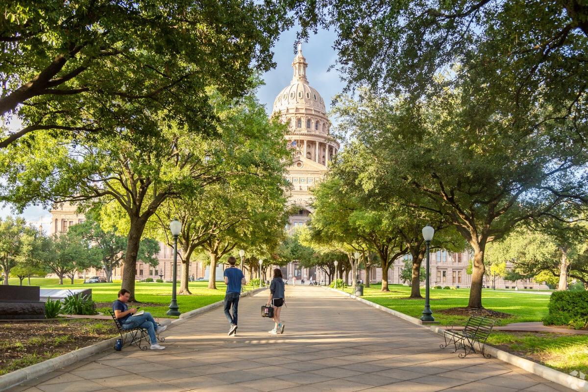 Pedestrians walk around the Texas State Capitol in Downtown Austin.
