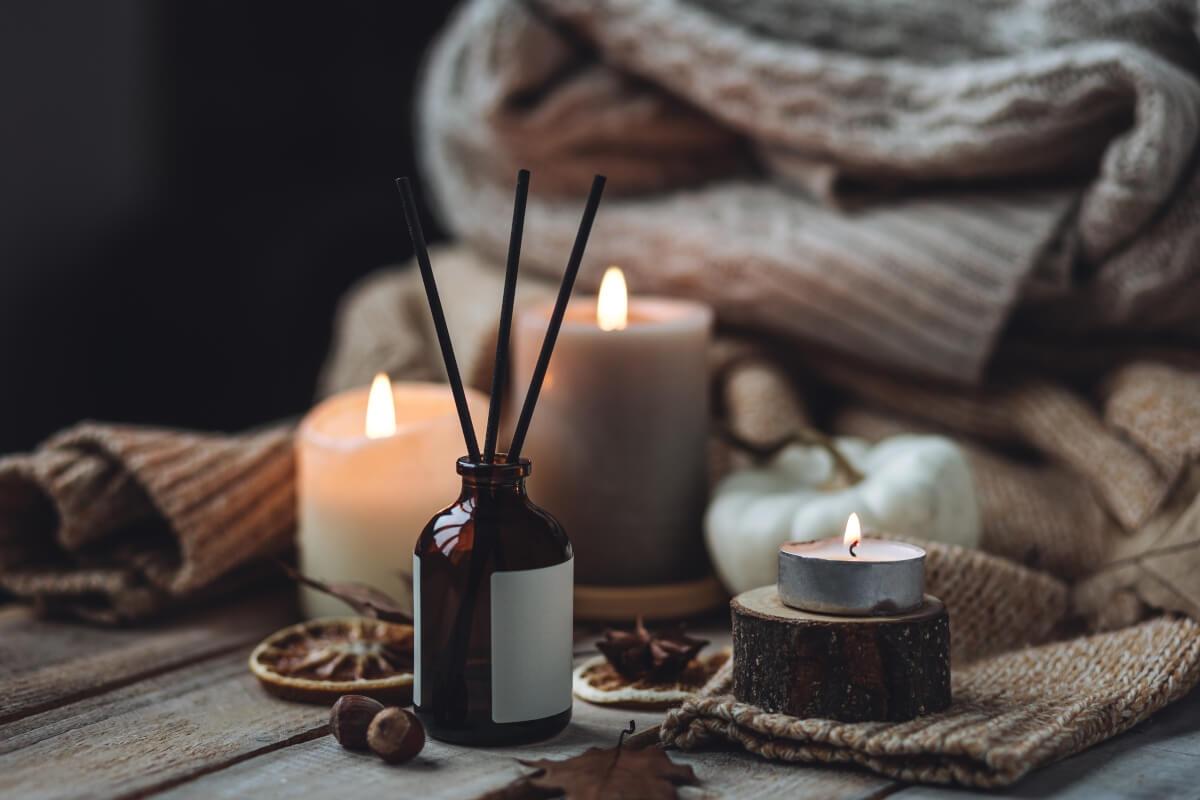 Candles and incense in front of a pile of sweaters.