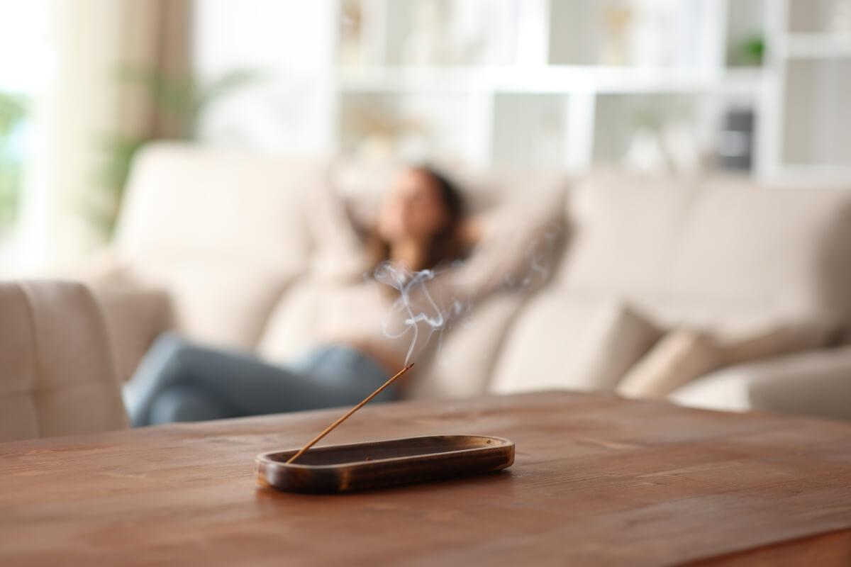 Woman burns incense in her apartment.