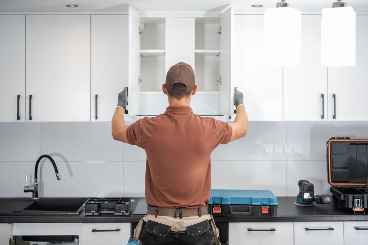 Contractor examines kitchen cabinets.