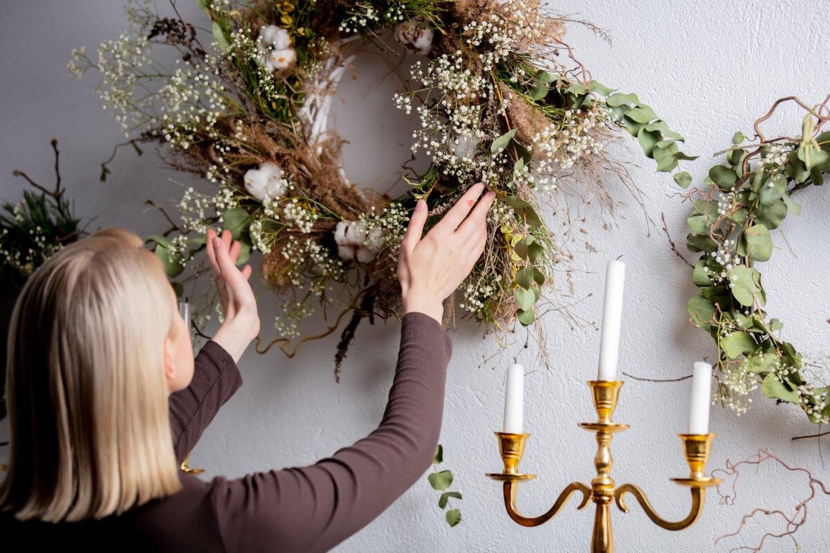 Woman hangs wreath in her apartment.