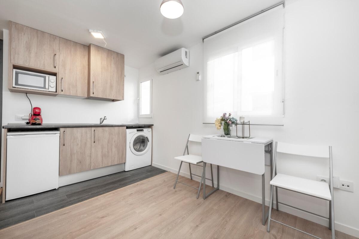 Small apartment with a washer, kitchen, and folding table.