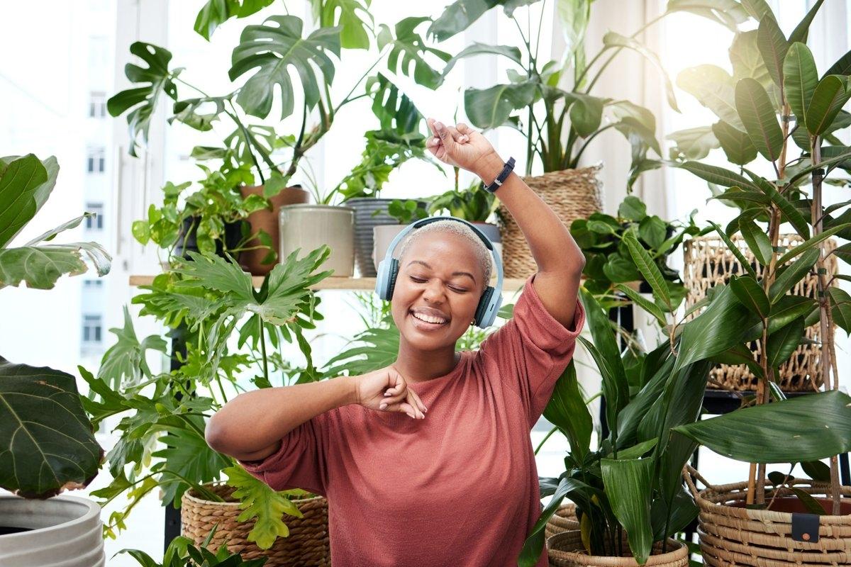 A lady dancing to music in front of her many house plants